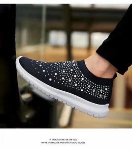 Primo piano di scarpe da ginnastica traspiranti in maglia da donna con strass lucidi.