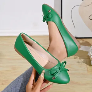 Detailed view of green pointed-toe ballet flats with elegant bow and pebbled texture.