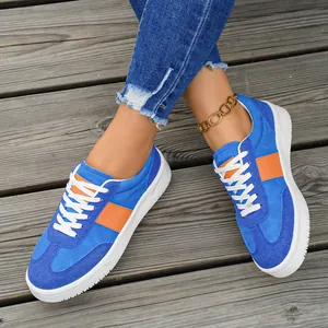 Vue détaillée de baskets en daim bleu et orange pour femme sur des planches bois.