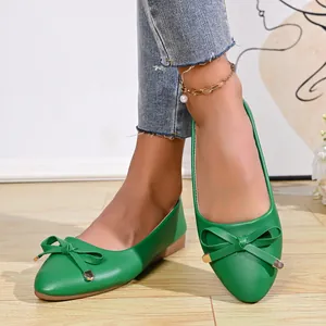 Detailed macro view of green pointed-toe ballet flats with elegant bow decoration