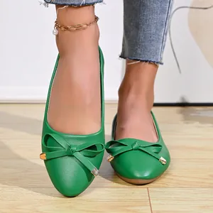 Close-up detail of vibrant green ballet flats featuring a decorative bow on the toe