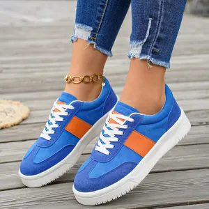 Baskets en daim bleu pour femmes avec rayures orange et semelles blanches épaisses.