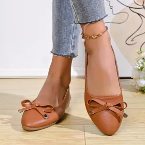 Close-up view of brown pointed toe flat shoes featuring elegant bow decoration on top.