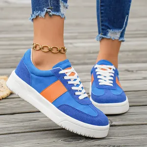 Vue détaillée de baskets en daim bleu et orange pour femmes sur un pont en bois