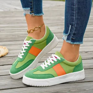 Vue détaillée de baskets pour femmes en vert et orange sur une terrasse en bois naturel.