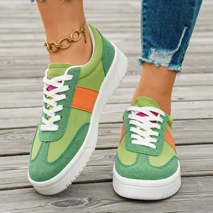 Gros plan de baskets décontractées pour femmes vert et orange sur une terrasse en bois