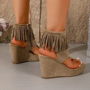 Gros plan de sandales compensées en daim taupe avec détails de franges style western