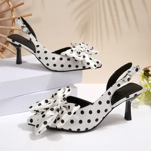 Détail d'escarpins slingback en satin blanc à pois noirs avec un grand nœud style français.