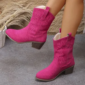 Close-up of fuchsia suede cowboy boots with elegant Western embroidery and chunky heels