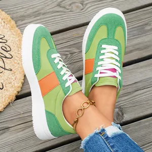 Détail macro de baskets décontractées vertes et orange pour femmes sur bois