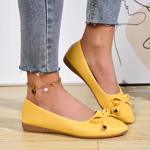 Elegant yellow French-style flat shoes with bow detail for women on light wood floor