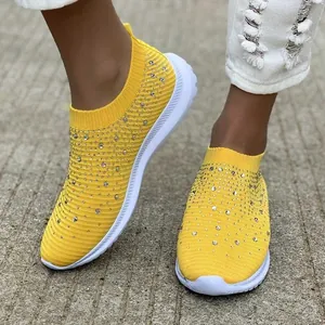 Vista dettagliata di sneaker fly-woven gialle traspiranti con strass scintillanti.