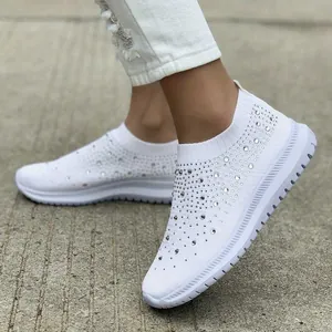 Dettaglio di sneakers bianche in maglia traspirante con decorazioni in strass scintillanti.