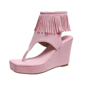 Détail de la sandale à talon compensé en daim rose avec des franges de style bohème