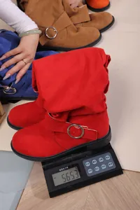 Macro view of red pleated suede Western boots on a digital scale showing weight details