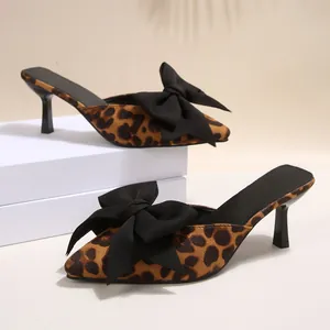 Détail de mules élégantes à imprimé léopard avec talons aiguilles et nœuds noirs