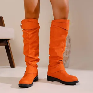 Close-up of bright orange slouched knee-high knight boots with buckle strap details.