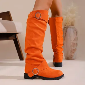 Side detail view of vibrant orange slouchy knee-high boots with silver buckles.