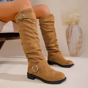 Detailed shot of stylish slouchy camel suede-like tall cowboy boots with silver buckle strap