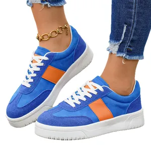 Baskets basses en daim bleu pour femmes avec rayure orange et semelle blanche épaisse.