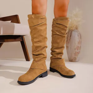 Close-up detail of tan slouchy western boots with buckle straps and suede texture