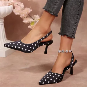 Vue latérale élégante de sandales à talons hauts en satin noir à pois sur un mannequin