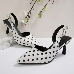 Gros plan de sandales à talons en satin blanc avec un élégant motif à pois noirs.