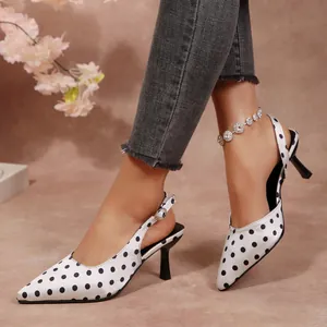 Gros plan sur des escarpins slingback en satin blanc à pois noirs et talon stiletto
