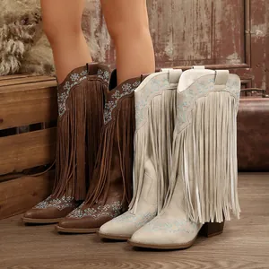 Detailed view of western cowboy boots featuring long fringes and geometric embroidery.