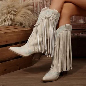 Close-up detail of vintage beige Western cowboy boots with long fringe and blue embroidery