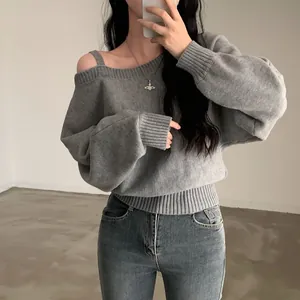 Dettaglio di un maglione a maglia grigio con spalle scoperte e polsini a coste larghi.