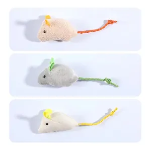 Trois jouets souris en peluche pour chat avec queues en corde colorées et herbe.