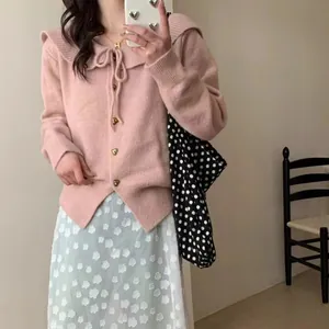 Close-up of a pink sailor collar knit cardigan featuring a bow tie and heart buttons
