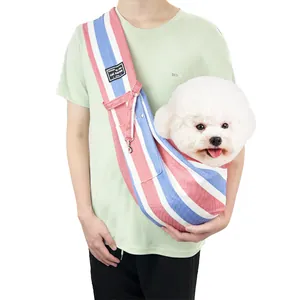 Close-up of a person wearing a red, white, and blue striped pet sling with a small dog