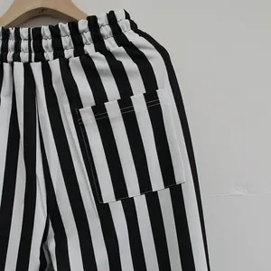 Close-up detail of black and white vertical striped sports pants with a back pocket.