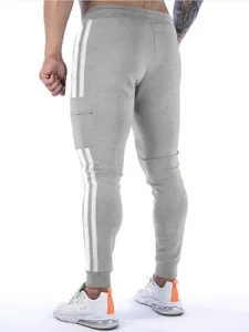 Detailed view of grey joggers with white side stripes and ribbed cuffs