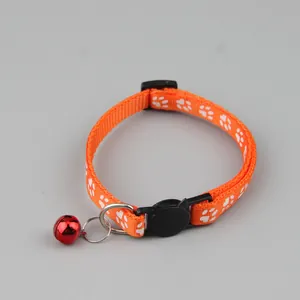 Gedetailleerd overzicht van een oranje kattenhalsband met witte pootafdrukken en een bel.