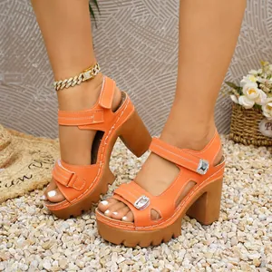 Chunky orange platform sandals featuring Velcro straps and silver buckle on pebbles