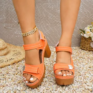 Detailed view of orange platform sandals with adjustable Velcro straps on pebbles.