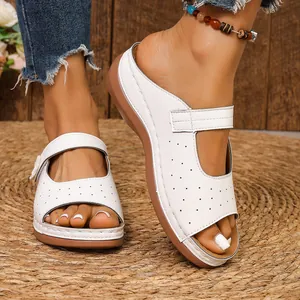 Detailansicht weißer Leder-Keilsandalen mit floralen Akzenten und feinen Perforationen