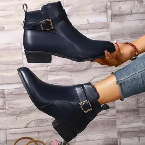 Detalle de los elegantes botines Chelsea azul marino con punta fina y hebilla dorada