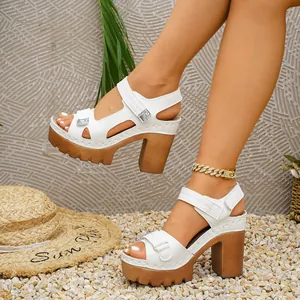 Stylish white platform sandals with chunky heels and Velcro straps worn on feet.