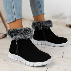 Close-up of black winter snow boots with grey faux fur trim worn with blue jeans.