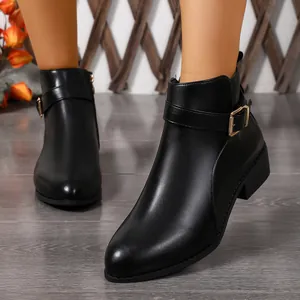 Detalle de elegantes botines negros de punta para mujer con correa de hebilla metálica