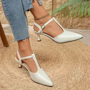 Primer plano de sandalias blancas de punta con tacón de gatito y detalle de T.