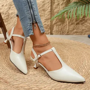 Detalle de sandalias blancas con punta afilada y tacón de gatito con diseño de correa en T