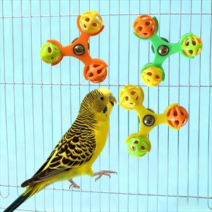 Nahaufnahme eines Wellensittichs, der mit farbenfrohen Glockenspielzeugen am Metallkäfig spielt