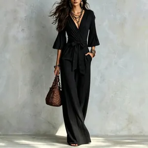 Detail showing the elegant black deep V-neck jumpsuit with bell sleeves and textured fabric