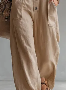 Detail shot showing the natural linen fabric texture of loose khaki utility overalls.