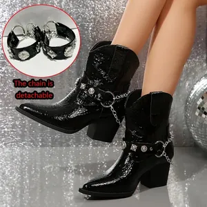 Détail de bottines noires effet croco avec une chaîne argentée amovible et clous